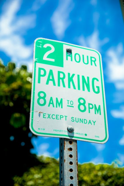 A vertical metal parking sign with a white background, green border, and green text indicating 'Reserved Parking' with a blue wheelchair symbol below, and a label 'Van Accessible' at the bottom. The s