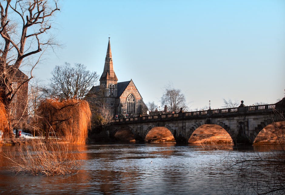A clear daytime view of Kingston town centre near Kingston Bridge, featuring a mix of historic and modern buildings with sandstone and brick facades, some with decorative windows and architectural det